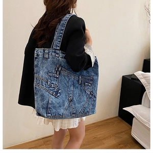 Detail shot of the deconstructed blue denim tote bag worn on shoulder by a model