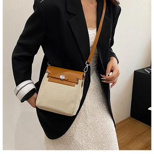 Detail of canvas and leather crossbody bag featuring a round metal lock and shoulder strap