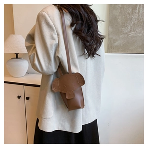 Detail of a brown elephant-shaped mini crossbody bag worn with a light grey blazer