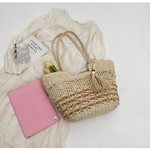 Detalle del bolso tote bohemio de paja con borlas y textura tejida bicolor
