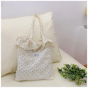 Detail of floral canvas tote bag featuring ruffled edges and delicate yellow flower patterns