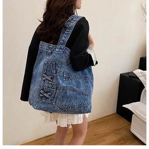 Detail of blue denim tote bag featuring side lace-up design and contrast stitching