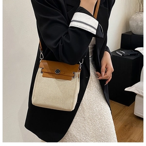 Detail of canvas and brown leather crossbody bag shown on model in a modern interior