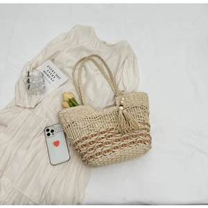 Detalle del bolso tote bohemio de paja con tejido de rayas y borla de cuentas de madera
