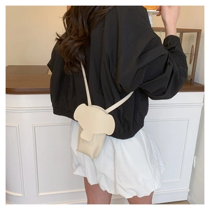 Rear view of model wearing a minimalist beige elephant-shaped crossbody shoulder bag