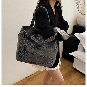 Detailed view of washed black denim tote bag with vintage stitching and pocket design