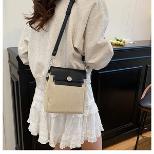 Detailed view of canvas and black leather crossbody bag with silver buckle on a model