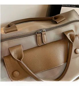 Close-up of smooth dual zippers and leather trim on khaki nylon travel bag
