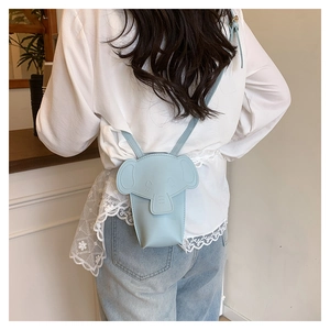 Detail shot of a light blue elephant-shaped crossbody bag worn by a model in a minimal setting