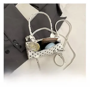 Internal capacity of white polka dot boston bag with phone, perfume, and cosmetics