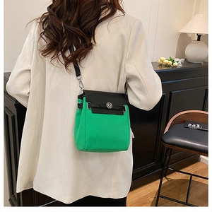 Detail of green and black canvas crossbody bag with silver hardware on female model