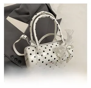 Detailed view of white polka dot cylinder handbag with lace bow and pearl charms