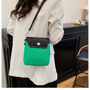 Detail view of green canvas crossbody bag with black leather flap and silver buckle