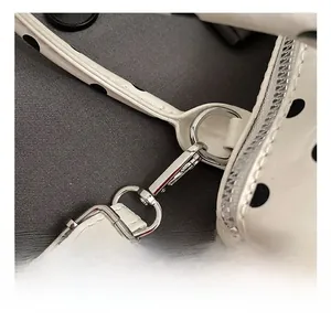 Macro detail of silver metal buckle and adjustable white polka dot patent leather strap