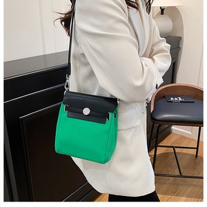 Detail of color-block crossbody bag featuring green fabric and black leather contrast