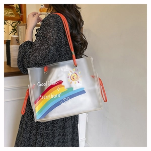 Detail of transparent PVC tote bag featuring rainbow graffiti and orange top handles