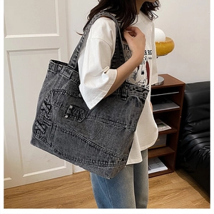 Detailed view of large washed denim tote bag with jeans-style pockets and side lacing