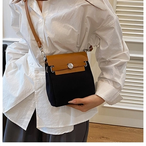 Close-up of the silver round lock and contrast leather strap detail on the bag