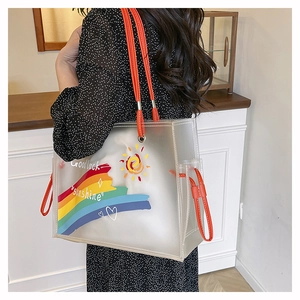 Detail of transparent PVC beach bag with rainbow print and orange leather handles