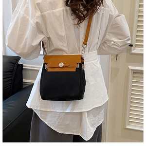 Detail of contrast canvas crossbody bag with round metal buckle and brown leather flap