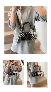 Close-up of black polka dot barrel handbag with tulle bow and pearl charm detail