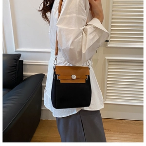 Close-up of contrast canvas shoulder bag with leather flap and iconic metal buckle detail