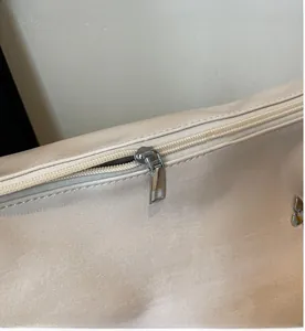 Close-up of a smooth silver metal zipper on a champagne beige minimalist tote bag