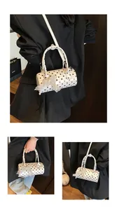 Close-up of a white polka dot cylinder handbag featuring a pearl lace bow charm detail