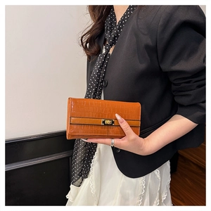 Détail de la pochette orange texture crocodile avec fermoir rotatif doré élégant
