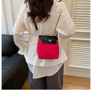 Detail of the magenta canvas crossbody bag with black leather flap and metal clasp closure