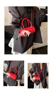 Close-up of red polka dot barrel bag featuring lace bow and pearl charm detail