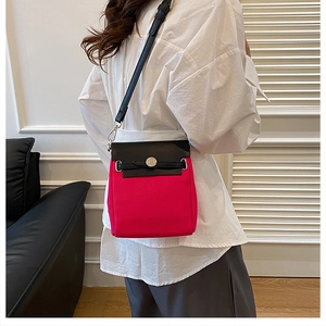 Detail of a pink and black canvas crossbody bag with silver buckle on a model