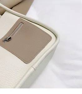 Detailed macro view of the cream lychee textured leather and brown contrast zipper pocket