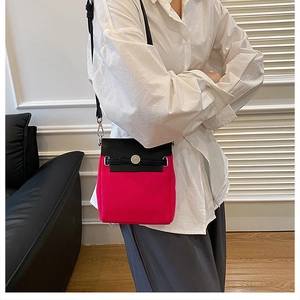 Detail of the rose red and black canvas crossbody bag with leather strap and metal buckle