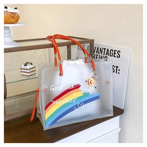 Frosted PVC tote bag detail with orange leather handles and sun rainbow pattern print