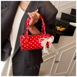 Detail of red polka dot cylinder handbag with white mesh bow and pearl charm