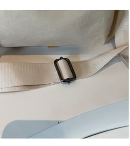 Detail of adjustable beige canvas strap with durable black metal buckle on shoulder bag