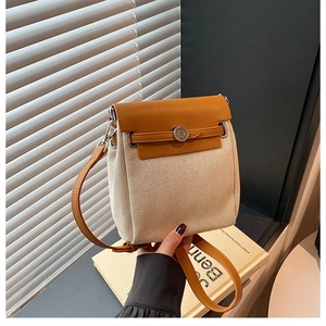 Detail of canvas and leather shoulder bag with silver round twist lock and flap closure