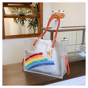 Detail of semi-transparent tote bag with orange handles and Good Luck sunshine print