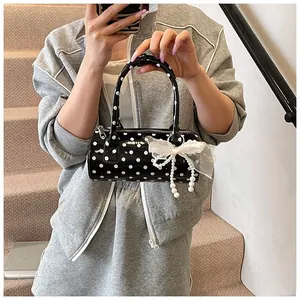 Close-up of polka dot cylinder handbag with lace bow and pearl charm detail