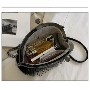 Interior capacity view of a black tassel shell bag with metal frame and chain strap