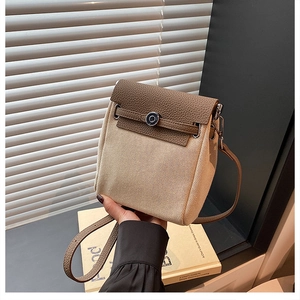 Detail of canvas crossbody bag with brown leather trim and metal lock closure