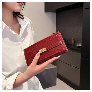 Détail d'une pochette en cuir verni bordeaux à motif crocodile et boucle dorée