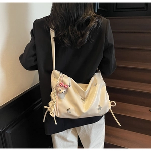 Detail of cream white tote bag with silver butterflies and plush rabbit pendant
