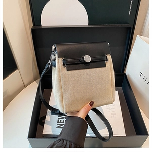 Detailed view of two-tone canvas crossbody bag with round metal buckle on gift box