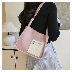 Pink lychee grain shoulder bag with contrast cream pocket shown in a lifestyle setting