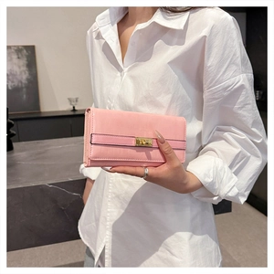 Détail d'une pochette rose façon croco avec un élégant fermoir rotatif doré rectangulaire