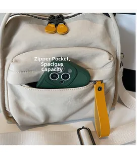 Detail view of beige canvas crossbody bag showing front zipper pocket with phone storage