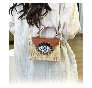 Detail of bohemian straw handbag with embroidered eye and fringe shown on model
