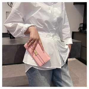 Détail d'un long portefeuille rose en cuir gaufré avec boucle dorée par un mannequin